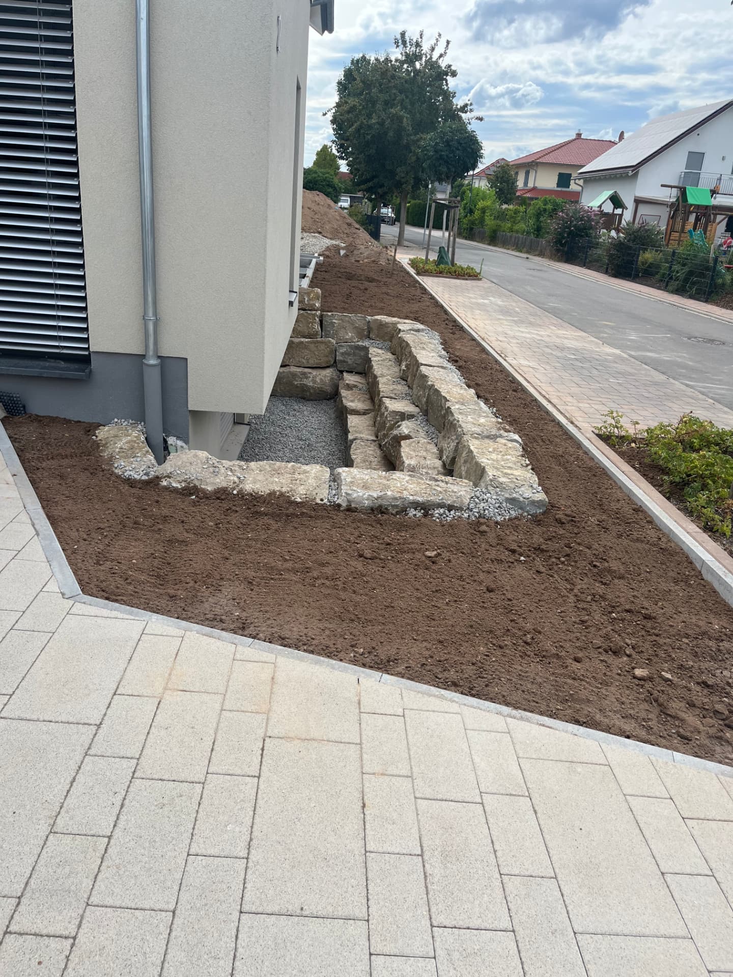 Natursteinmauer und gepflasterter Weg im Neubau-Garten